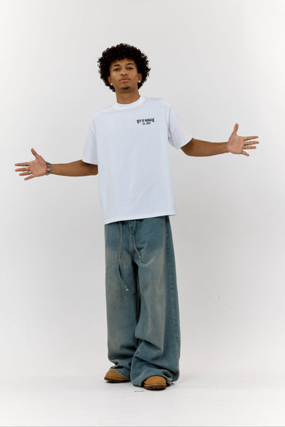Person wearing a white t-shirt and blue jeans standing with arms outstretched on a white background