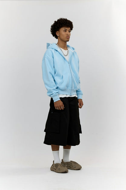 Person wearing a light blue hoodie, black skirt, and brown shoes on a white background