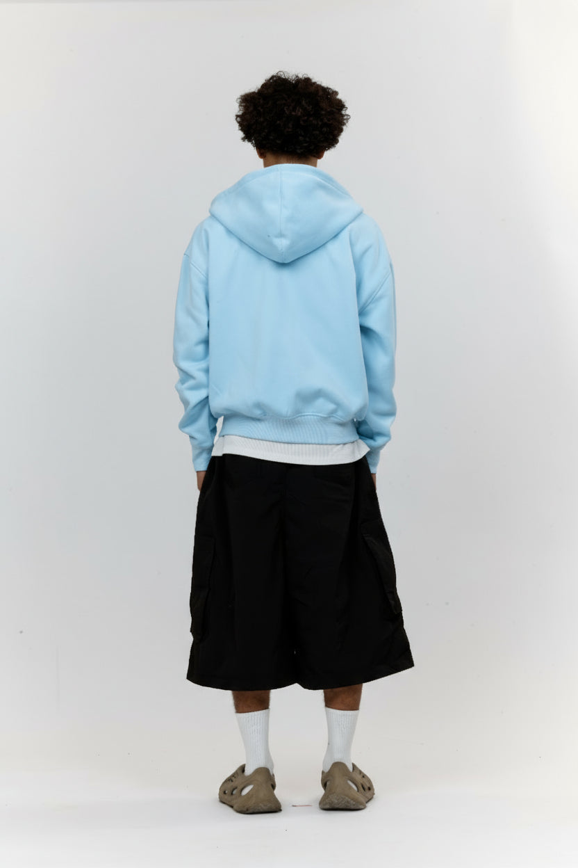 Person wearing a light blue hoodie and black skirt on a white background