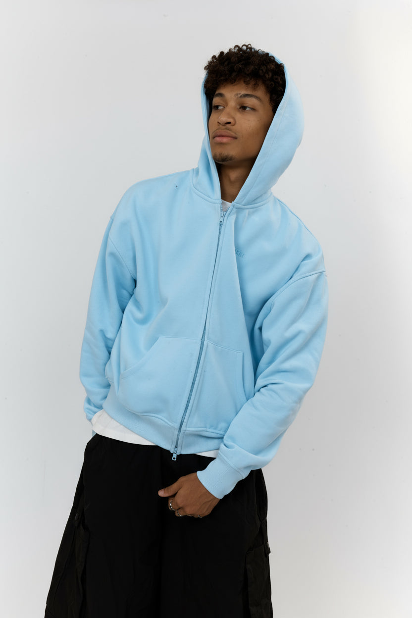 Person wearing a light blue hoodie against a white background
