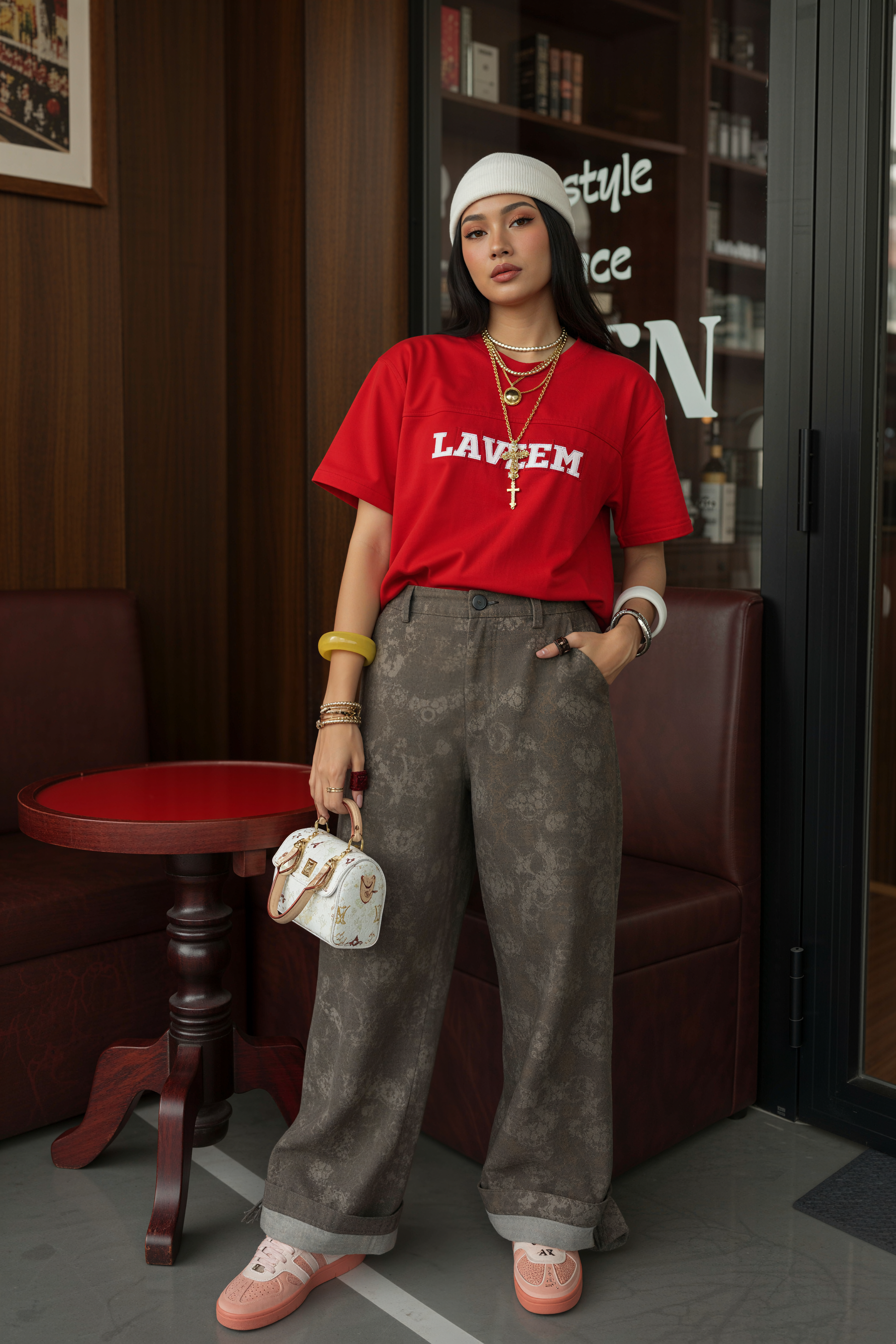 Person wearing a red shirt with white text, gray pants, and pink shoes in an indoor setting.